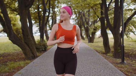 Athletic fit sport runner girl training marathon run, listening music in earphones. Workout cardio...