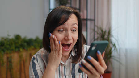 Wow. Happy winner woman freelancer use mobile smartphone typing browsing say Yes found out great big...