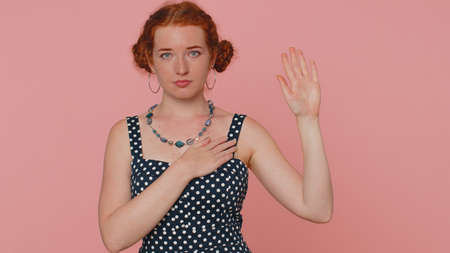 I swear to be honest. Sincere responsible redhead woman raising hand to take oath, promising to be...