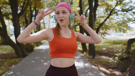 Athletic fitness sport runner girl training exercise, listening music on headphones dancing to...