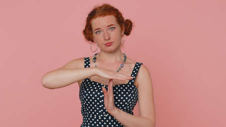 Time out. Tired serious upset young redhead woman in dress showing pause break gesture, limit or stop sign, no pressure, I need more time. Ginger girl with freckles isolated on pink studio backgroundの写真素材