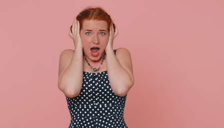 Scared fearful redhead woman covering ears with hands, closing eyes, meeting her own phobia,...
