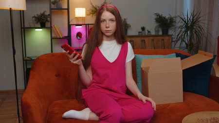 Angry dissatisfied shopper teen redhead children girl unpacking parcel feeling upset confused with...