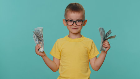 Little toddler children boy holding fan of cash money dollar banknotes celebrate dance, success business career, lottery game winner, big income, wealth. Young preschool kid on blue studio backgroundの写真素材