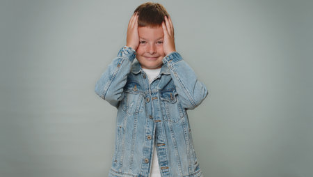 Sincere toddler children boy in jacket wishing, waiting for good luck and loses becoming surprised sudden lottery results, bad news, fortune loss fail. Young teenager child isolated on gray backgroundの写真素材