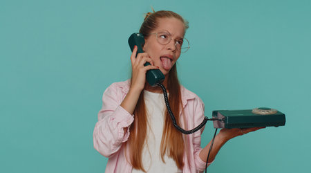 Crazy pretty teenager girl child kid talking on wired vintage telephone of 80s, fooling, making...