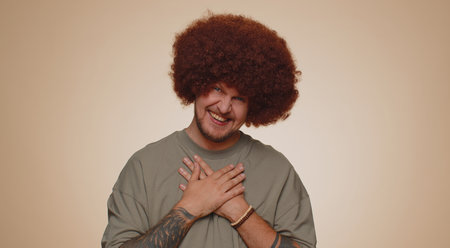 Joyful man with lush hairstyle laughing out loud after hearing ridiculous anecdote, funny joke,...