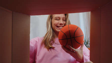 Happy surprised winner girl unpacking delivery parcel at home. Smiling satisfied young woman...