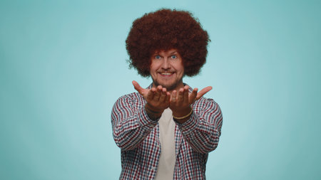 Free gifts and presents for you. Man opening hands, glad to see, excitement, preparing surprise, sharing love emotions, congratulating. Young adult guy isolated alone on blue studio wall backgroundの写真素材