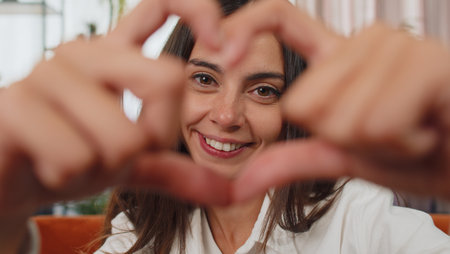 I love you. Adult girl makes symbol of love, showing heart sign to camera, express romantic feelings, express sincere positive feelings. Charity, gratitude, donation. Young woman close-up happy faceの写真素材