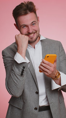 Happy excited joyful business man use mobile cell phone typing browsing shouting say wow yes found out great big win, good news, lottery jackpot goal achievemen, celebrating success, winning. Verticalの写真素材