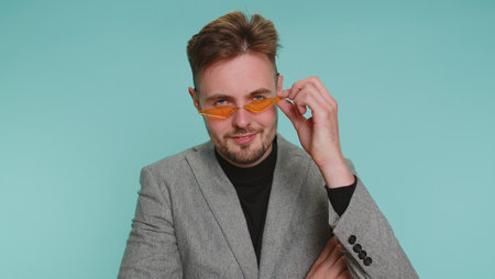 Playful happy bearded business office man in formal suit wearing yellow sunglasses blinking eye...