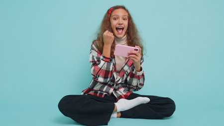 Worried young preteen child girl kid enthusiastically playing racing or shooter video games on smartphone. Excited little cute preteen children using mobile phone gadget app with drive simulatorの写真素材