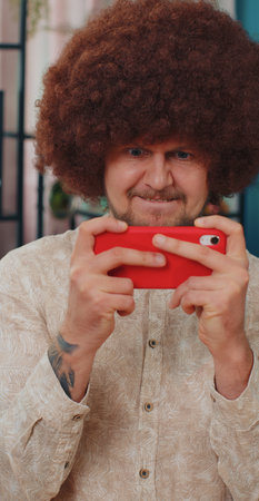Portrait of caucasian adult man enthusiastically playing racing or shooter video games on...