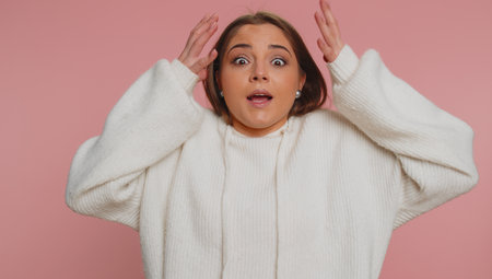 Oh my God, Wow. Excited amazed winner woman raising hands in surprise looking at camera with big eyes, shocked by sudden victory. Sincere young adult girl isolated alone on pink studio backgroundの写真素材