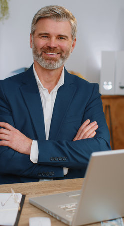 Confident happy mature businessman looking at camera with smile at home office desk workplace. Face...