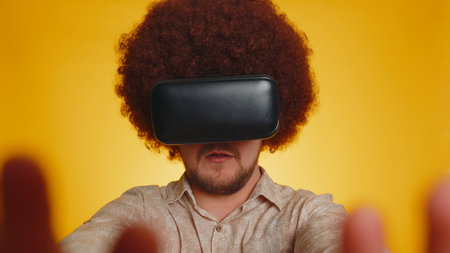 Redhead bearded man with lush afro hairstyle using headset helmet app to play simulation innovation...