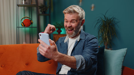 Middle-aged old man use mobile smartphone typing browsing say Wow yes found out great big win good...