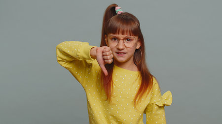 Dislike. Upset young preteen child girl kid showing thumbs down sign gesture, expressing discontent,...