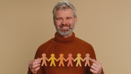 Man showing multiracial different skin color human shape cut out of paper, concept of teamwork,...