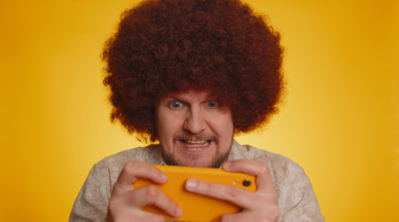 Worried bearded man with afro hairstyle coiffure enthusiastically play racing or shooter video games...