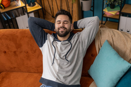 Tired man lying down on comfortable couch, taking a rest, daytime nap. Portrait of carefree...