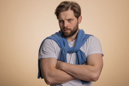 Caucasian man in t-shirt screams yell from stress tension problems feels horror hopelessness fear panic surprise shock expresses gestures rage. Handsome young guy isolated on beige studio backgroundの写真素材