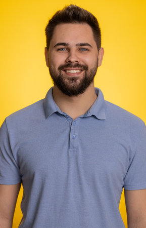 Portrait of happy calm caucasian man smiling friendly, glad expression looking at camera dreaming resting, relaxation feel satisfied concept good news celebrate win. Guy on yellow background. Verticalの写真素材