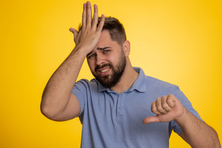 Bearded caucasian man feeling hopelessness loneliness, nervous breakdown, loses becoming surprised by lottery results, bad fortune loss, unlucky news. Young guy isolated on studio yellow backgroundの写真素材