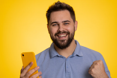 Happy excited joyful caucasian man in t-shirt use smartphone typing browsing shouting say wow yes found out great big win, good news, lottery goal achievemen, celebrating success, winning gameの写真素材
