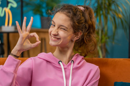 Okay. Happy cheerful preteen school girl looking approvingly at camera showing ok gesture, positive...