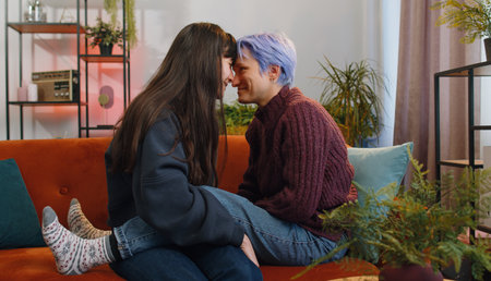 Portrait of two young lesbian women family couple. Girls embrace hug each other at home indoor. LGBT people. Romantic love relationship concept and emotion. Gay woman caressing touches her girlfriendの写真素材