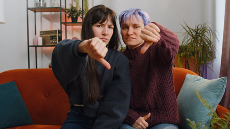 Dislike. Upset two lesbian women family couple or girls friends showing thumbs down sign gesture,...