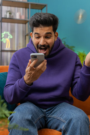 Happy indian man use mobile smartphone typing browsing say Wow yes found out great big win good news...