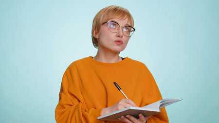 Thoughtful journalist woman making notes, writing down thoughts with pen into notepad notebook...