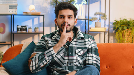 Shh be quiet, hush please. Indian man with presses index finger to lips makes silence hush gesture...