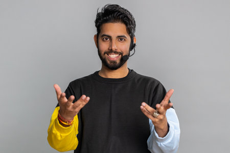 Smiling indian man wearing headset, freelance worker, call center or support service operator...