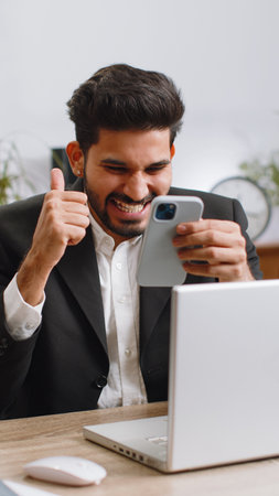 Happy amazed indian businessman working on smartphone shocked by sudden victory game winning lottery...