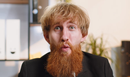 Oh my God, Wow. Happy amazed young bearded businessman working on laptop shocked by sudden victory,...