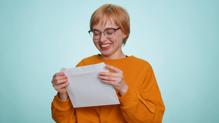 Pretty young woman open envelope take out letter reads it feel happy. Blonde girl career growth...
