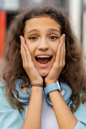 Oh my God, Wow. Preteen child kid looking surprised at camera with big open eyes, shocked by sudden victory, game winning, lottery goal achievement, good news outdoors. Girl in city street. Verticalの写真素材