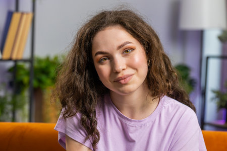 Portrait of happy calm young woman at home couch smiling friendly, glad expression looking away...