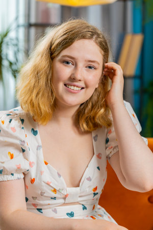 Portrait of happy calm young redhead woman at home couch smiling friendly glad expression looking dreaming resting, relaxation feel satisfied concept good news, celebrate win. Girl in room. Verticalの写真素材