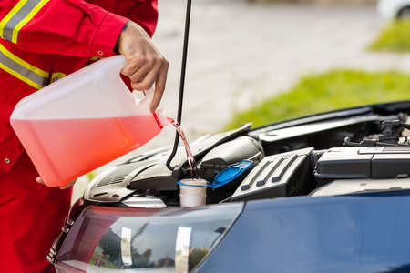 Close-up service worker man driver pouring non freezing windshield cleaning glass washer fluid into...