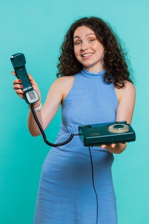 Hey you, call me back. Young woman talking on wired landline vintage telephone of 80s, advertising...