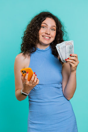 Young woman looking smartphone display sincerely rejoicing win, receiving money dollar cash...