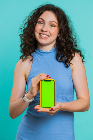 Young developer business woman holding smartphone with green screen chroma key mock up recommend good application promotional sale offer. Freelancer girl isolated on blue studio background. Verticalの写真素材