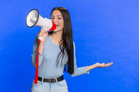 Happy Caucasian young woman talking with megaphone, proclaiming news, loudly announcing...