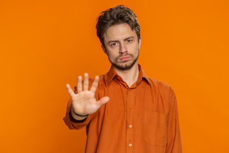 Stop, enough. Caucasian man say no hold palm hands in finish gesture, warning of finish, prohibited...