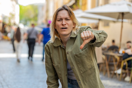 Dislike. Upset young woman showing thumbs down sign gesture, expressing discontent, disapproval,...